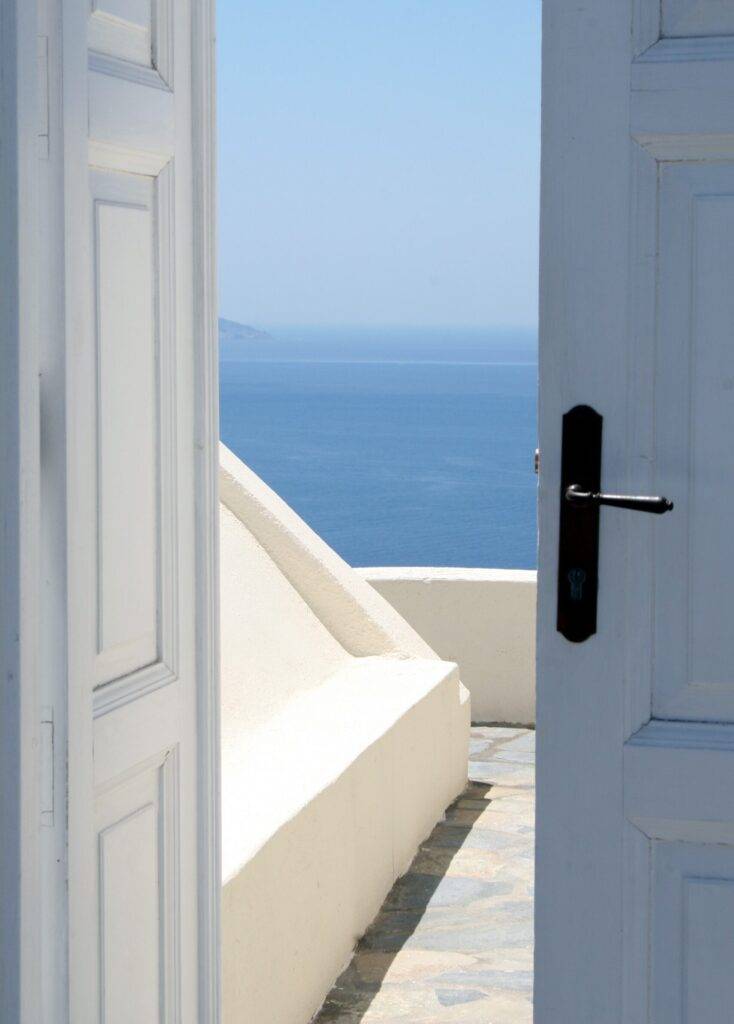 una porta bianca aperta con vista dall'interno sul mare, come un'apertura per uscire dalla stanza della mente
