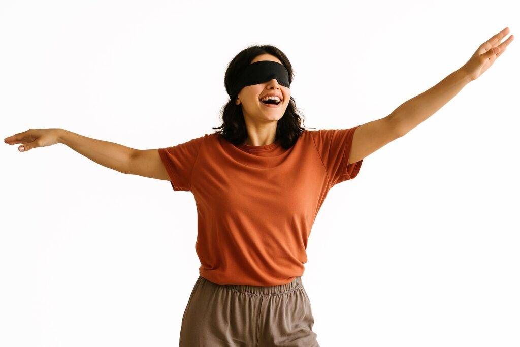 Blindfolded girl wearing a black mask, arms outstretched and ecstatic expression, practising osho nataraj meditation.
